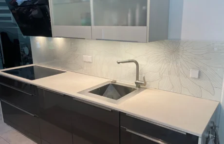 Moderne Küchenarbeitsplatte mit Gasherd, Aufkantung aus Metall, hängendem Topflappen, Steckdosen und Oberschränken.